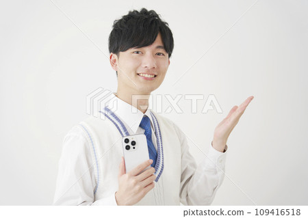 High school boy holding a smartphone and pointing to the right side with his palm, white background High school boy holding a smartphone and pointing to the right side with his palm, white background 109416518