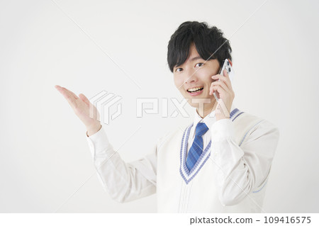 High school boy pointing to the left side with his palm while calling on a smartphone, white background 109416575