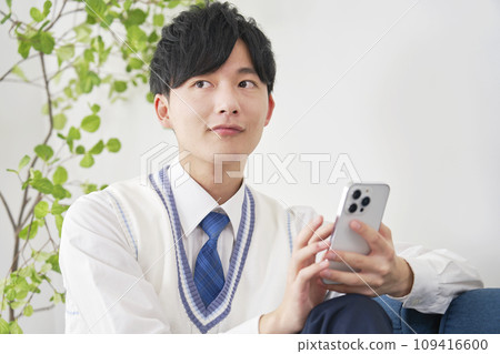 High school boy using smartphone in living room High school boy using smartphone in living room 109416600
