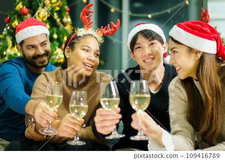 Group of diverse ethnicity young people enjoy celebrating a Christmas and New Year party together with a lot of foods and drinks. Friends celebrate Christmas and New Year festival and drink a wine. 109416789