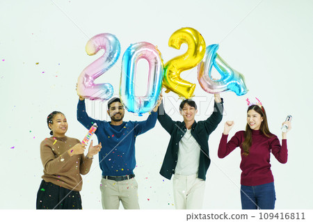 Group of diverse ethnicity young people celebrating Christmas and new year party together, men and women showing a fantasy balloon over their head in number of a year 2024 and firing a paper firework. 109416811