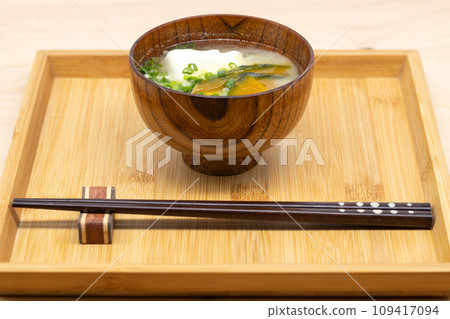 Pumpkin and tofu miso soup served on a wooden tray with a serving of chopsticks 109417094