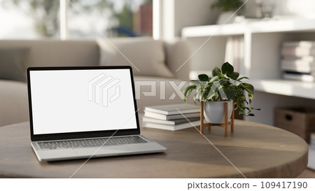 A white-screen laptop mockup on a wooden coffee table in a modern bright living room. A white-screen laptop mockup on a wooden coffee table in a modern bright living room. 109417190