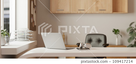 A modern home office or private office with a laptop, headphones, and a book on a white desk. 109417214