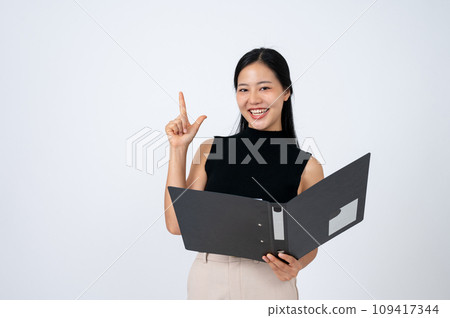 A positive businesswoman is pointing her finger up, got an idea while reading document in a binder. A positive businesswoman is pointing her finger up, got an idea while reading document in a binder. 109417344
