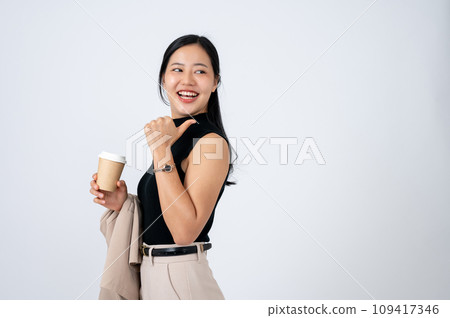 A beautiful Asian businesswoman is pointing her thumb backward at an empty space on white background A beautiful Asian businesswoman is pointing her thumb backward at an empty space on white background 109417346