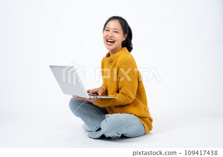 Happy and beautiful Asian woman sits on the floor on an isolated white background with her laptop. Happy and beautiful Asian woman sits on the floor on an isolated white background with her laptop. 109417438