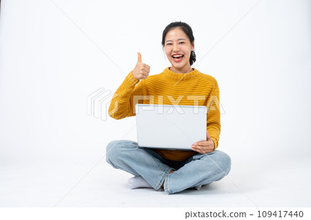 Happy woman sits on the floor on an isolated white background with her laptop and showing thumb up. Happy woman sits on the floor on an isolated white background with her laptop and showing thumb up. 109417440