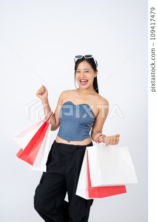 Young elegant Asian woman is standing on an isolated studio white background with shopping bags. 109417479