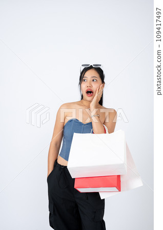 An elegant Asian woman with her shopping bags is stunned and surprised with shopping discount. An elegant Asian woman with her shopping bags is stunned and surprised with shopping discount. 109417497