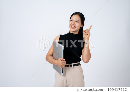 A beautiful Asian businesswoman holding a laptop, pointing her finger up, isolated white background. 109417512