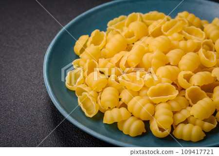 Raw durum wheat gnocchi pasta with salt and spices in a ceramic plate Raw durum wheat gnocchi pasta with salt and spices in a ceramic plate 109417721