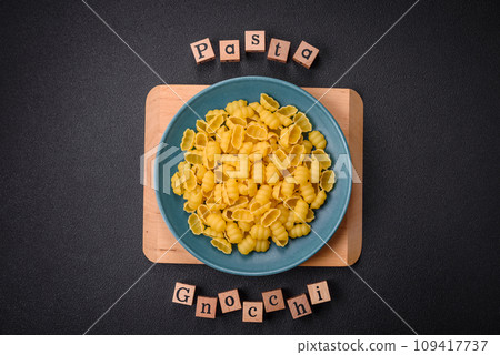 Raw durum wheat gnocchi pasta with salt and spices in a ceramic plate Raw durum wheat gnocchi pasta with salt and spices in a ceramic plate 109417737