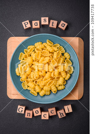Raw durum wheat gnocchi pasta with salt and spices in a ceramic plate Raw durum wheat gnocchi pasta with salt and spices in a ceramic plate 109417738
