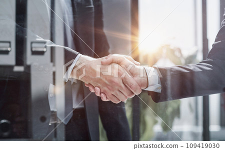 executives shaking hands in front of their manager and a colleague executives shaking hands in front of their manager and a colleague 109419030