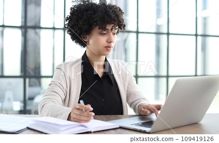 Portrait of Young Successful Caucasian Businesswoman Sitting at Desk Working on Laptop 109419126