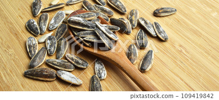Roasted and salty organic sunflower seeds on wooden spoon Roasted and salty organic sunflower seeds on wooden spoon 109419842