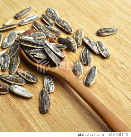 Roasted and salty organic sunflower seeds on wooden spoon Roasted and salty organic sunflower seeds on wooden spoon 109419843