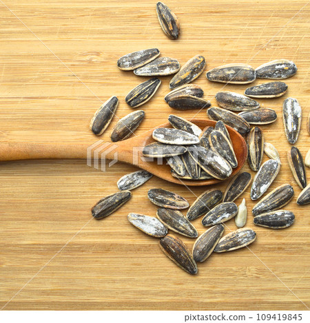 Roasted and salty organic sunflower seeds on wooden spoon Roasted and salty organic sunflower seeds on wooden spoon 109419845