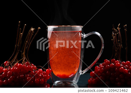 Hot viburnum tea in a glass cup with a double bottom on a black background. 109421462