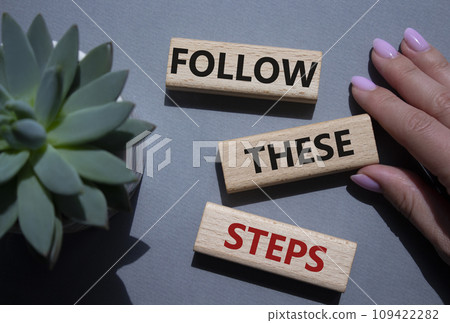 Follow these steps symbol. Wooden blocks with words Follow these steps. Beautiful grey background with succulent plant. Businessman hand. Business and Follow these steps concept. Copy space. 109422282