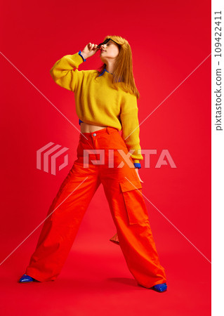 Full length portrait of attractive young lady dressed retro style bright outfit with sunglasses posing against vivid red background. Full length portrait of attractive young lady dressed retro style bright outfit with sunglasses posing against vivid red background. 109422411