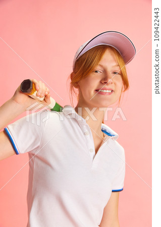 Close up portrait of beautiful red-haired woman, professional tennis sportsman posing with racquet against pastel pink background Close up portrait of beautiful red-haired woman, professional tennis sportsman posing with racquet against pastel pink background 109422443