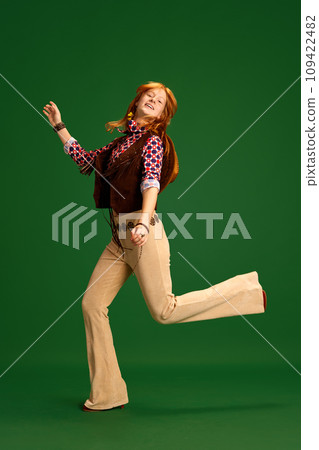 Adorable, charming girl, teenager with red hair dressed old-fashioned western style outfit posing against green studio background. Adorable, charming girl, teenager with red hair dressed old-fashioned western style outfit posing against green studio background. 109422482