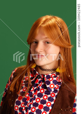 Close-up portrait of red haired cheerful, smiling young cowgirl, teenager looking at camera against green studio background. 109422485