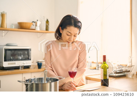 一個女人在廚房裡喝葡萄酒 一個女人在廚房裡喝葡萄酒 109423610
