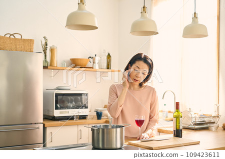 A woman drinking wine in the kitchen A woman drinking wine in the kitchen 109423611