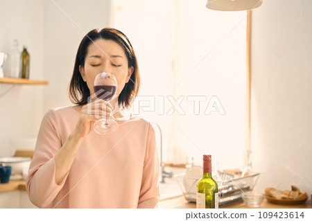 A woman drinking wine in the kitchen A woman drinking wine in the kitchen 109423614