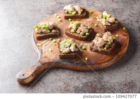 Healthy rye bread with canned cod liver, capers and green onions close-up on a cutting board. Horizontal Healthy rye bread with canned cod liver, capers and green onions close-up on a cutting board. Horizontal 109427077