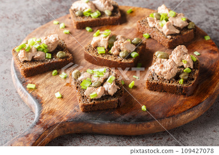 Homemade rye bread sandwiches with cod liver, capers and green onions close-up on a cutting board. Horizontal Homemade rye bread sandwiches with cod liver, capers and green onions close-up on a cutting board. Horizontal 109427078
