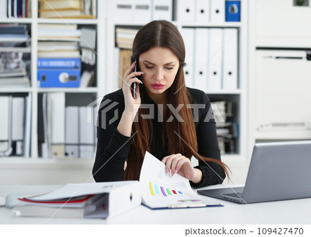 Beautiful brunette smiling businesswoman hold in arm cellphone Beautiful brunette smiling businesswoman hold in arm cellphone 109427470