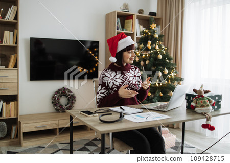 Female professional in Santa hat talking to client over video call on Christmas. 109428715