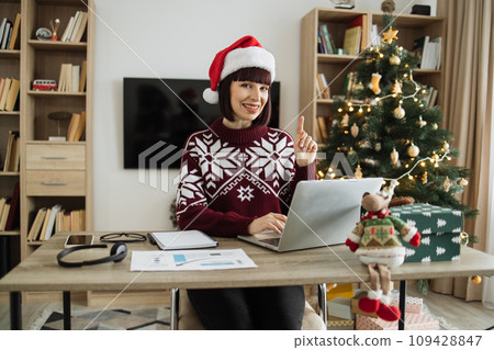 Thoughtful Caucasian businesswoman in Santa hat and warm sweater 109428847