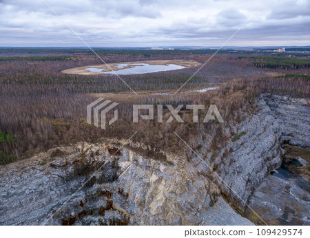 Stone quarry in the forest. Flying over the autumn mixed forest during sunset. The surroundings of Yekaterinburg. Ural, Russia, Aerial View Stone quarry in the forest. Flying over the autumn mixed forest during sunset. The surroundings of Yekaterinburg. Ural, Russia, Aerial View 109429574