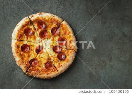 A slice of hot Italian pizza with stretching cheese. Pizza pepperoni on a dark background 109430105