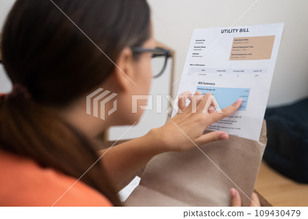 Concentrated woman in glasses checks domestic finances serious lady manages monthly budget and does tax paperwork at workplace in light accommodation 109430479