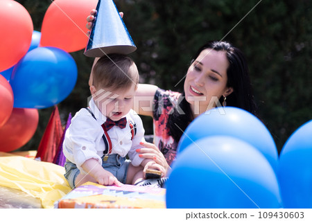Stylish mother little son birthday party, vibrant first birthday celebration. Balloons, party hats, and other delightful decorations enhance the joyful ambiance. Stylish mother little son birthday party, vibrant first birthday celebration. Balloons, party hats, and other delightful decorations enhance the joyful ambiance. 109430603