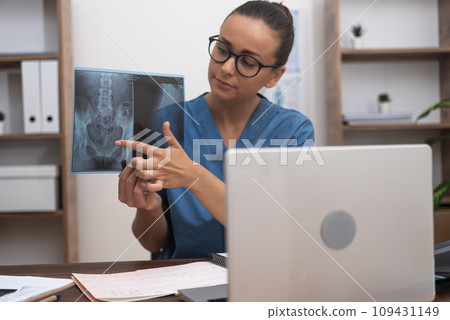 Through a video call, the doctor exhibits X-ray films on a laptop screen, providing the patient with an understanding of the disease's attributes as a facet of telemedicine. Through a video call, the doctor exhibits X-ray films on a laptop screen, providing the patient with an understanding of the disease's attributes as a facet of telemedicine. 109431149