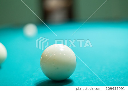 A green billiard table with balls lying on it without people. A beautiful billiard table stands in an empty room with white balls lying on it. Empty billiard table concept with balls. A green billiard table with balls lying on it without people. A beautiful billiard table stands in an empty room with white balls lying on it. Empty billiard table concept with balls. 109433991