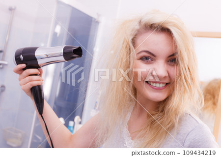 Woman drying hair in bathroom Woman drying hair in bathroom 109434219
