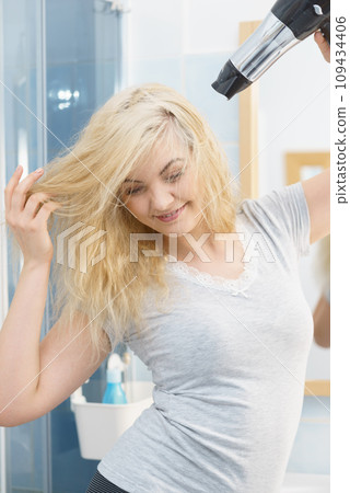 Blonde woman using hair dryer 109434406