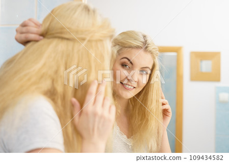 Woman in bathroom styling hair 109434582