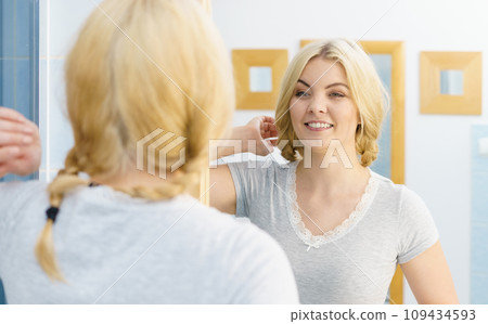 Woman in bathroom styling hair 109434593