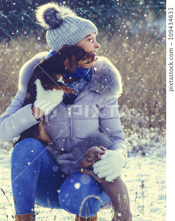 Woman playing with dogs during winter Woman playing with dogs during winter 109434631