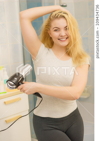 Woman drying sweat stains using hair dryer Woman drying sweat stains using hair dryer 109434736