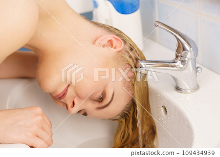 Woman washing hair in bathroom sink Woman washing hair in bathroom sink 109434939